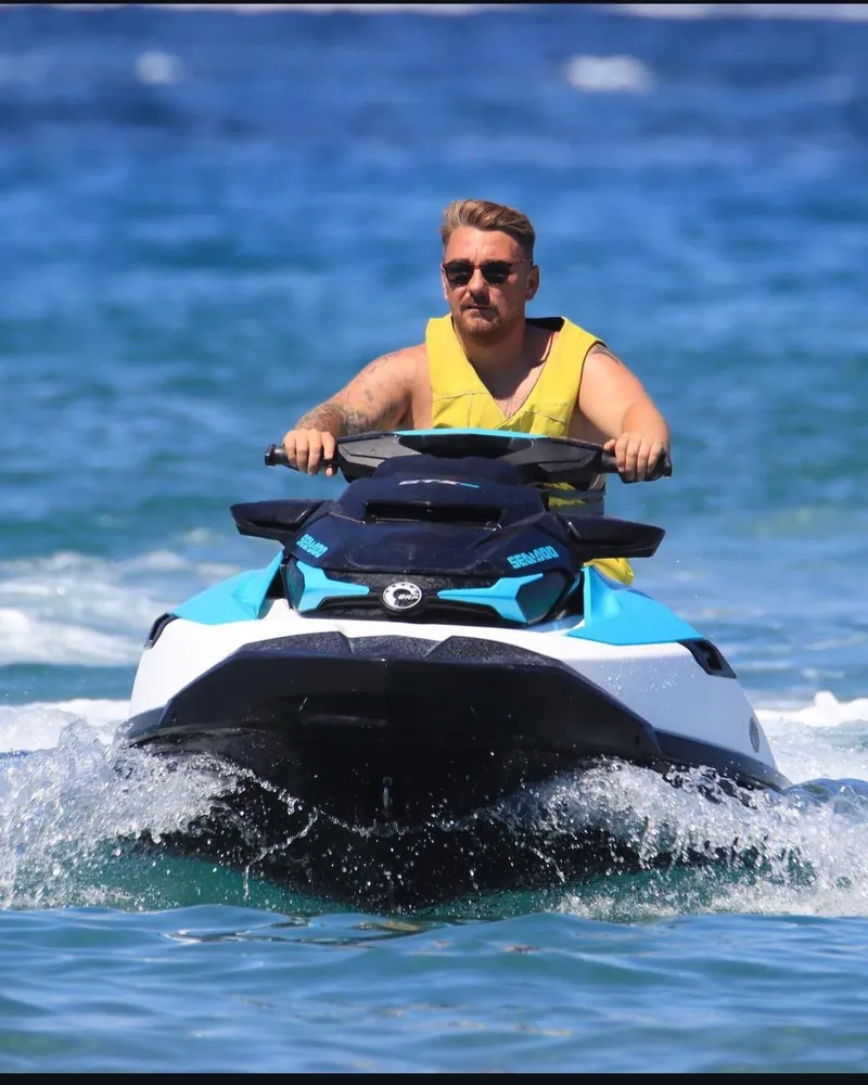 Matthew riding a jet ski in a yellow life jacket
